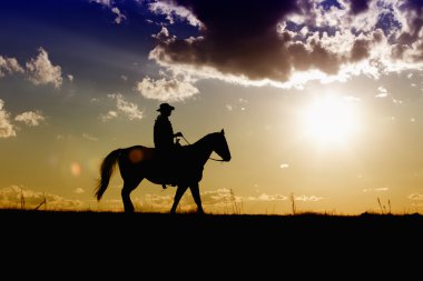 Ranch hand on horse at sunset clipart