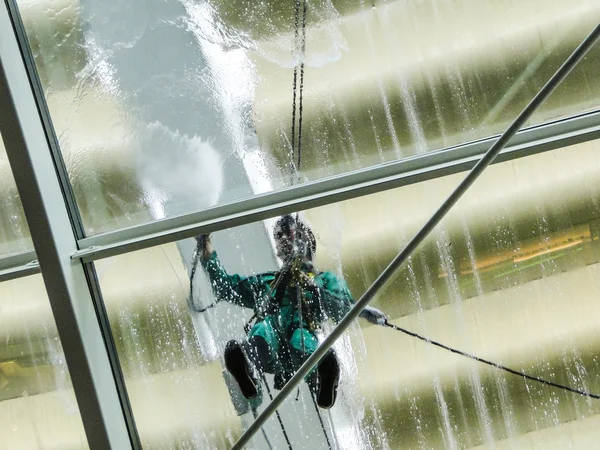 Homem na pressão de trabalho lavando um telhado de vidro — Fotografia de Stock