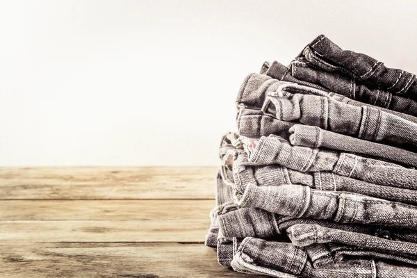 fashionable clothes. pile of jeans on a wooden background. grain