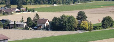 Tarlaları, ağaçları ve evleri olan düz bir manzara.