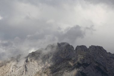 Bir dağın tepesinin ve bulutların manzarasını kapat.