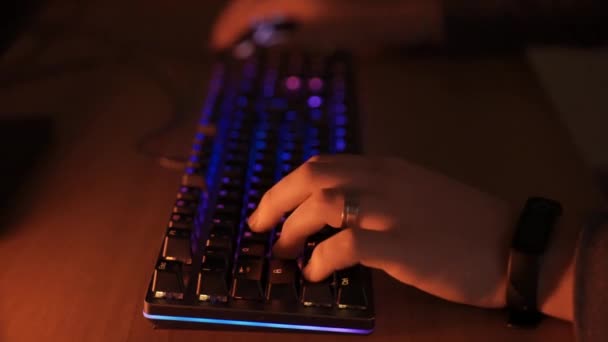 Oyuncuların elleri bilgisayar klavyesinde RGB 'nin arka aydınlatması eşliğinde yazarken profesyonel video oyunları oyuncusu evde sanal siber oyunlar oynayarak zaman geçiriyor. Profesyonel siber oyun konsepti — Stok video