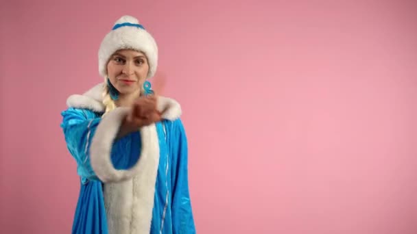 Mavi Noel Baba kostümü giymiş Noel Baba, pembe arka planda parmak işareti göstermiyor. Ciddi bir kadın kameraya bakarken duygularını gösteriyor. Duygular ve işaretler kavramı — Stok video