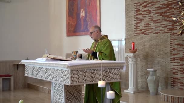 Cassino,イタリア- 2020年10月18日:コロナウイルスのパンデミックと社会的距離中のイタリアの地方教会での宗教儀式のプロセス、祭壇の横に立つ地元の司祭と神聖な保持 — ストック動画