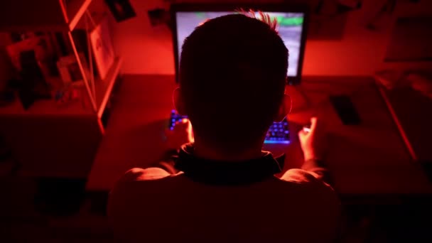 Voltar visão tiro de jogador profissional masculino sentado dia e noite no quarto escuro iluminado com luz de néon vermelho e jogar jogos de vídeo cibernéticos RPG no PC poderoso. Campeonato de jogos de tiro virtual no ciberespaço — Vídeo de Stock