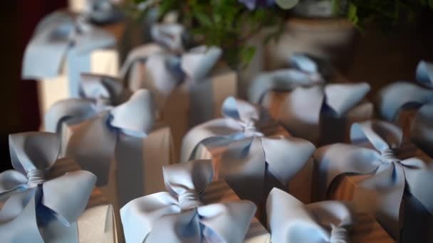 Großaufnahme von kleinen Pappschachteln mit blauem Band, die für die Feier der Taufe vorbereitet wurden, berühmte Bonbonniere-Geschenke mit verschiedenen Konfetti drinnen am Banketttisch. Dankbare Geschenke für Eingeladene — Stockvideo