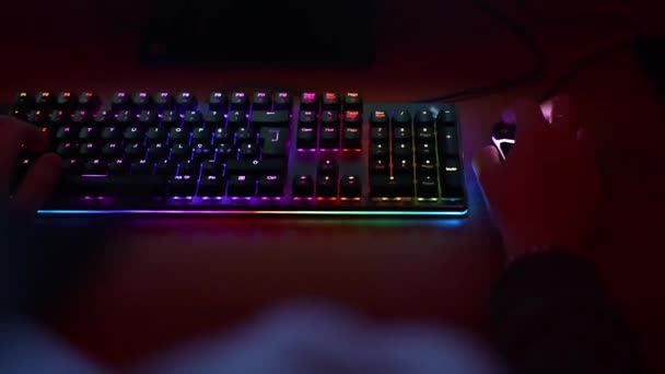 Oyuncuların ellerinin bilgisayar klavyesinde RGB arka ışıklandırması ve aydınlatılmış bilgisayar faresine tıklayarak yazışması. Profesyonel oyuncu evde bilgisayar oyunu oynuyor, teknoloji eğlence konsepti — Stok video