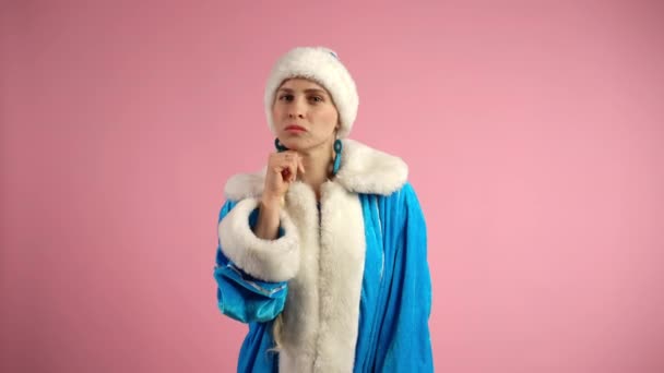 Pembe arka planda dalgın bir Kar Kızı, geleneksel mavi Noel kostümlü ciddi bir kadın hüzün duygularını gösteriyor, hayal kırıklığına uğramış, sorunlu düşünen kadın rolünü oynayan Noel Baba Kadın. — Stok video