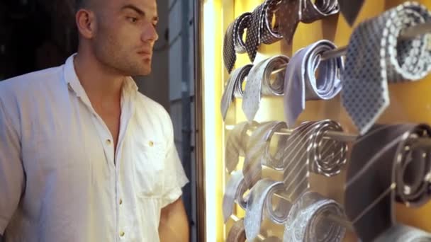 Gros plan de vitrine illuminée avec collection de cravates pour hommes chères. Jeune homme intéressé debout devant le magasin et regarder la nouvelle marque de cravates de luxe, choix masculin shopoholic — Video