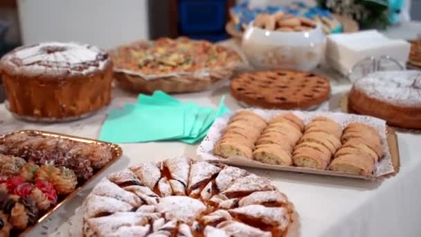 Berbagai kue panggang dan biskuit dengan topping buah-buahan yang berbeda dan dekorasi yang disiapkan di meja perjamuan untuk acara perayaan. Meja penutup untuk tamu yang diundang, kue yang ditaburi dengan — Stok Video