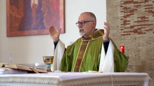 CASSINO, ITALIË - OKTOBER 18, 2020: Lokale priester van provinciale Italiaanse stad Cassino houdt in handen heilige kelk en bord boven het altaar, pastoor het lezen van de Heilige Schrift en het bidden van God. Italiaans — Stockvideo