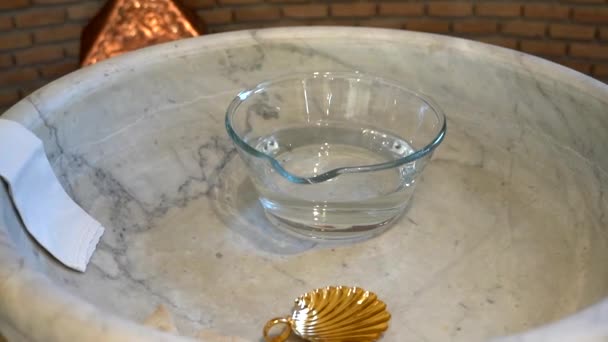 Close-up of marble baptism font with holy water prepared for newborn baby christening in church. Catholic and orthodox rites of baptism, religious ritual of initiation into the faith of the Christian — Stock Video