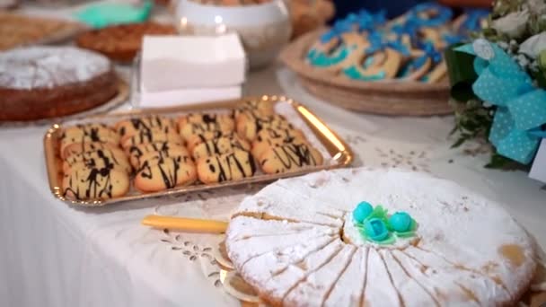 Surtido de diferentes pasteles horneados y galletas en mesa buffet, deliciosos pasteles dulces espolvoreados con azúcar en polvo y decorados con flores de azúcar azul. Banquete de postres para la celebración de fiestas — Vídeos de Stock