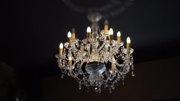 Obrovský křišťálový lustr visící na stropě domu v tmavé místnosti, krásný vinobraní lustr s diamanty detaily a LED světla ve svícnu. Světelná křišťálová lampa na stropě — Stock video