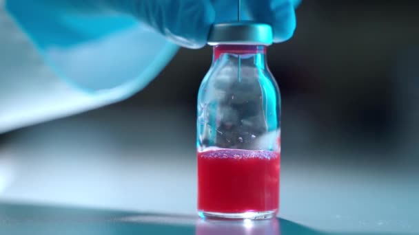 Laboratorní vědec v ochranných rukavicích pracujících s chemickými roztoky, chemik podávající činidlo s injekční stříkačkou v injekční lahvičce s práškem a získávající obtížnou chemickou sloučeninu léků červené tekutiny — Stock video