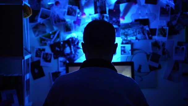 Widok z tyłu strzał zawodowy męski gracz siedzi w ciemnym pokoju z migającymi kolorami światła przed ekranem PC i gra RPG cyber gier wideo, skoncentrowany mężczyzna gra strzelanka, biorąc udział w — Wideo stockowe