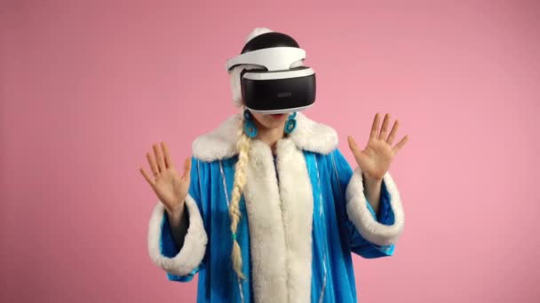 현대의 가상 현실 안경을 쓴 젊은 여성이 고립 된 핑크 배경 위에 서 있습니다. 집중 된 여성은 VR 비디오 게임에 몰두하고 있습니다. 실내에서 의 3D 가상 현실이죠. 증강현실 헤드셋 — 비디오