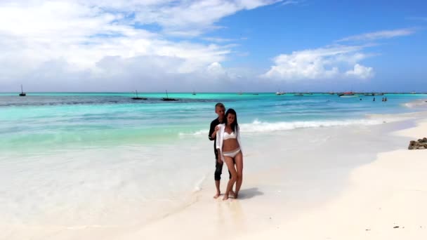 Dança romântica de jovem casal apaixonado na praia do mar, menina sexy em biquíni branco mostrando seu verdadeiro amor e emoções ao dançar com seu namorado. Amantes sexy dançando na praia de areia lavada — Vídeo de Stock