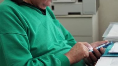 Ofiste dosya yığınları ve tamamlanmamış kağıtların arasında çalışan yaşlı bir adam. Çalışırken cep telefonu kullanan yetişkin işçiler, internette gezinen, haberleri okuyan, sohbet eden ve...