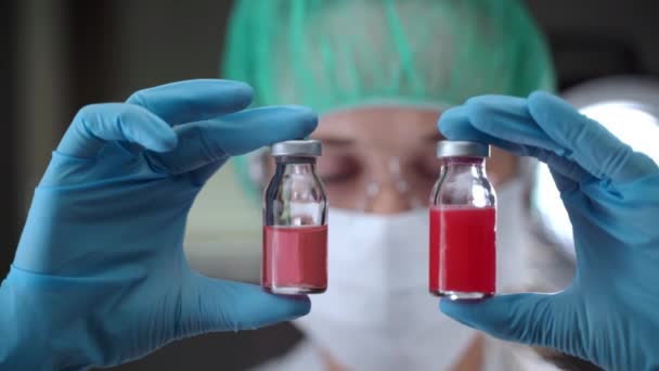 Ważne badania naukowe w laboratorium w celu opracowania skutecznej szczepionki przeciwko zakażeniu koronawirusami. Kobieta chemik w ubraniu ochronnym posiadająca dwie sterylne fiolki z potencjalną szczepionką — Wideo stockowe
