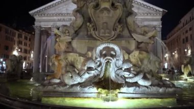 Roma 'nın göbeğinde gece vakti akan suyla aydınlatılmış antik mermer çeşme, açık ağızlı hayvan heykelleri. Meydanın önündeki Ortaçağ Roma Çeşmesi