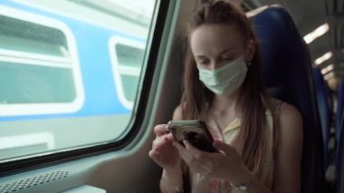 Koronavirüs salgını sırasında trenle seyahat eden koruyucu maskeli yorgun bir kadın, kamusal alanlarda ve ulaşımda kurallara ve sosyal mesafeye uyan bir kadın. Tıbbi maske takan genç adam