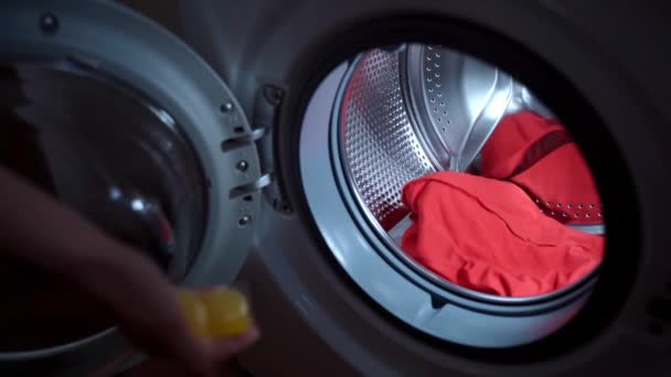 Housewife preparing dirty laundry with stains for washing, womans hand throwing two liquid concentrated capsules of washing detergent into the spinning cylinder and closing washing machine door — Stock videók