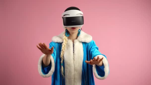 Jogos de vídeo interativos modernos através de fones de ouvido de realidade virtual, mulher interessada usando óculos de realidade aumentada em fundo rosa isolado dentro de casa. Inovações online modernas no mercado cibernético — Vídeo de Stock