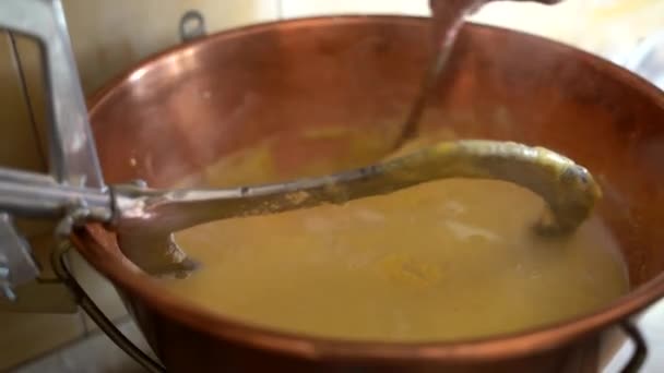 사람 이나무 숟가락을 들고 서서히 노란 폴렌타를 집에서 낮은 불에 구워진 구리 가마솥에 넣고 젓는다. 이탈리아 북부 지방의 전통적 인 이탈리아 요리를 준비 한다. 달콤 한 겨울 — 비디오