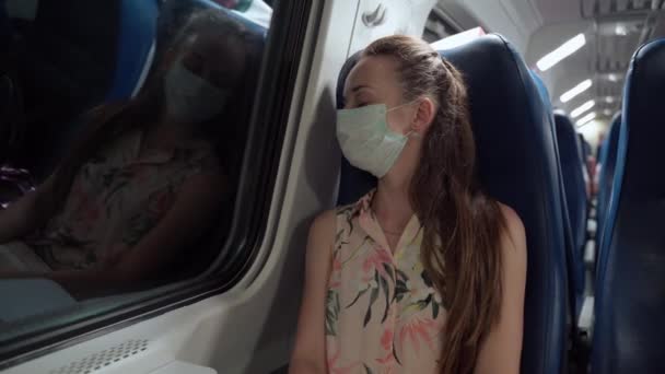 Προληπτικά μέτρα στις δημόσιες συγκοινωνίες και τους χώρους, πρόληψη της μόλυνσης από τον ιό του στομίου και εξάπλωση στο πλήθος. Κοινωνική απόσταση κατά τη διάρκεια covid-19, γυναίκα σε ιατρική μάσκα ύπνου κατά την οδήγηση με τρένο — Αρχείο Βίντεο