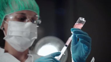 Laboratuvarda klinik analiz yapan kadın sağlık çalışanı steril şişeden şırınga dolduran biyokimyacı. Test için enjeksiyon hazırlanıyor, gezegen konsepti