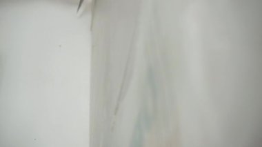 İnşaat alanındaki tamirat işleri, koruyucu eldivenli mühendis metal spatulayla duvarı spatulayla kaplıyor, duvarın yüzeyini beyaz alçı macunu çözeltisiyle düzleştiriyor ve hizalıyor.