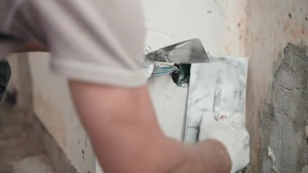 Ремонтник, использующий металлические лопатки и лопатки для штукатурки стены квартиры белым штукатуркой, опытный строитель, разбрасывающий вокруг распределительной коробки внешние кабельные провода. Выравнивание стены в — стоковое видео
