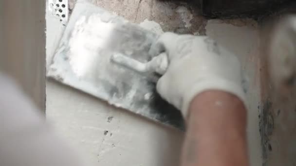 Gros plan des travailleurs à la main en utilisant une spatule métallique et une solution de pâte à tartiner pour les murs et les angles de mastic, réparateur plâtrage mur de ciment sous la fenêtre sur le chantier de construction — Video