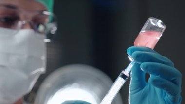 Laboratuvarda klinik analiz yapan kadın sağlık çalışanı steril şişeden şırınga dolduran biyokimyacı. Test için enjeksiyon hazırlanıyor, gezegen konsepti