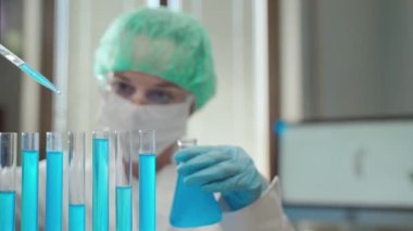 Kimyasal elementler ve farklı reaksiyonlarla virüs laboratuarında çalışan tıbbi koruyucu giysi araştırmacısı cam steril test kullanarak bilimsel deneyler yapan laboratuvar çalışanı.