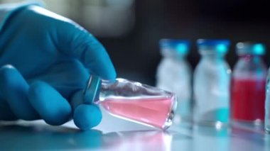 Şırıngayı şeffaf bir şişeden açık kırmızı solüsyonla doldurma işlemi. Profesyonel araştırmacıların ellerinde aşı geliştirmek için kimyasal deneyler var. Gezegen aşısı kavramı