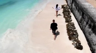 Neşeli mutlu evli çift, beyaz kum ve turkuaz suyla Maldivler kıyılarında koşuyor. İnsanlar balaylarını egzotik doğası olan muhteşem tropik adada geçiriyorlar.