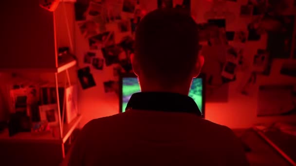 Vista posterior de un jugador profesional irreconocible sentado en una habitación oscura iluminada con luz de neón roja y jugando a videojuegos RPG cibernéticos y celebrando torneos con jugadores virtuales en una PC poderosa. Virtual — Vídeo de stock