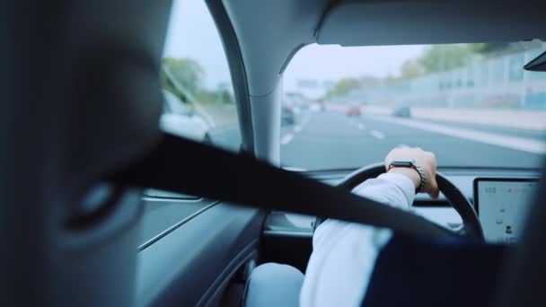 Onherkenbare zakenman in luxe kleding en met hoge kosten horloge besturen van een auto met vaste veiligheidsgordel, achteraanzicht van verantwoordelijke man volgens alle verkeersregels tijdens het rijden over de — Stockvideo