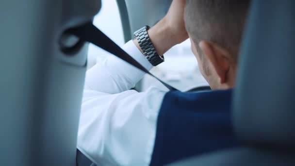 Visão traseira do homem de condução em um carro, homem de negócios cansado voltar para casa depois do dia de trabalho duro. Masculino em roupas de luxo segurando uma mão no volante do carro enquanto dirige, e colocando a outra — Vídeo de Stock