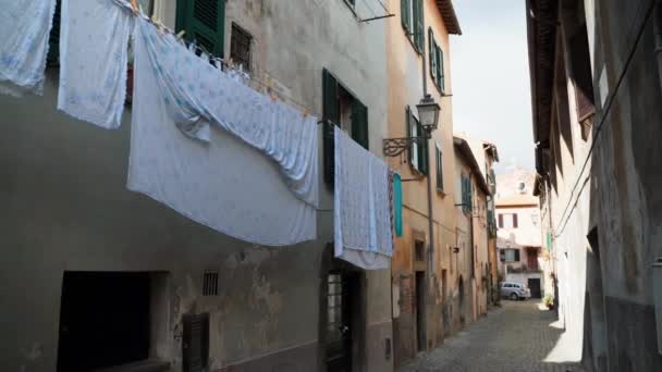 Hermosa calle estrecha en un antiguo pueblo Tuscania de la provincia de Viterbo, increíble ambiente medieval con el edificio exterior y colgando de la ropa al aire libre. Cultura italiana, pueblos del patrimonio — Vídeos de Stock