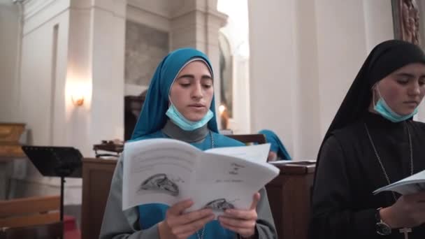 TUSCANIA, VITERBO - OKTOBER 31, 2020: Kerkelijk koor van nonnen neemt deel aan huwelijksceremonie voorstelling in oude tempel in Tuscania dorp, religieuze zusters in soutane en beschermende gezichtsmaskers — Stockvideo