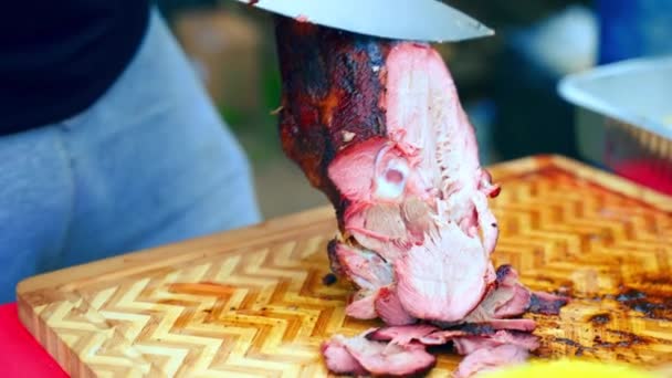 Festa tradizionale del barbecue all'aperto, chef irriconoscibile che affetta lentamente la coscia di agnello fumante con coltello da cucina, osso di agnello con crosta croccante preparata sulla griglia del fumatore. Gustosi pezzi di carne di agnello arrosto per — Video Stock