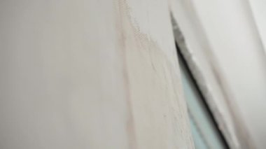 Yeni satın alınan apartmanın inşaat alanındaki duvarın yakın çekimi, bina ustasının metal spatula ile duvarı tutturması ve alçı macunu solüsyonunu tamamlaması. İşlem