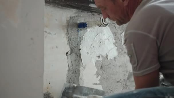 Réparateur crachant vieux mur de ciment déchiqueté sous la fenêtre à l'aide de truelle métallique, spatule et pâte de plâtre blanche, surface de mur nivellement homme avec mastic stuc. Restauration des murs, concept de révision — Video