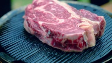 Yavaş çekimde ızgara ızgara ızgara ızgara bifteği, alevler, kömür külleri ve geleneksel Amerikan bbq partisi için açık havada kırmızı çiğ biftek hazırlama. Kanlı biftek ızgarası.