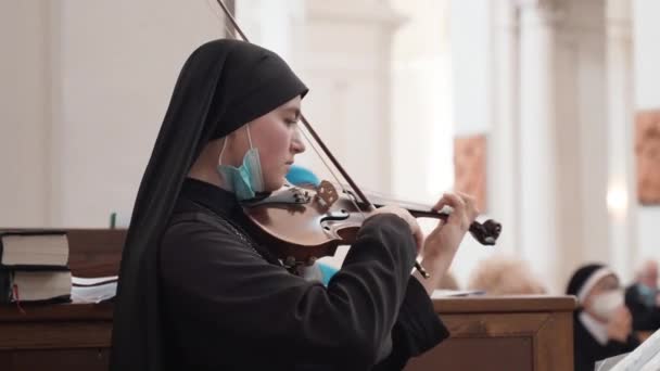 TUSCANIA, VITERBO - OCTOBER 31, 2020: 비테르보 지방의 토스카나 마을에서 종교 음악가가 연주하는 오래 된 교회에서 검은색 외투를 입고 바이올린을 연주하는 순종적 인 수녀 — 비디오