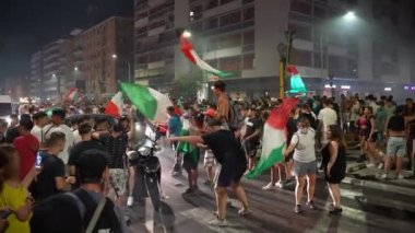 ROME, ITALY - 6 Temmuz 2021: İtalyan sokak futbolu taraftarlarından oluşan öfkeli kalabalık İtalyan spor takımının UEFA EURO 2020 'deki İspanyol takımına karşı zaferini kutluyor. Mutlu adamlar caddeleri kapatıyor, duruyor