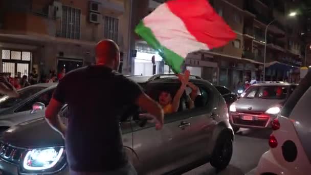 ROME, ITALIE - 6 JUILLET 2021 : Heureux fans italiens célébrant la victoire de l'équipe sportive en demi-finale UEFA EURO 2020 contre l'équipe espagnole de football, les conducteurs de voitures passant dans les rues romaines bondées avec — Video